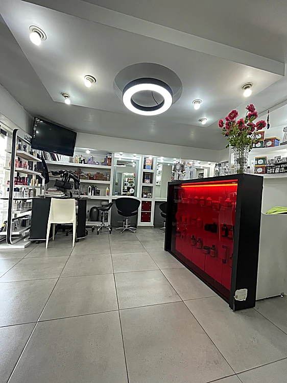 Interior del salón: nichos blancos, aro de luz en el techo y el mostrador rojo iluminado con rosas