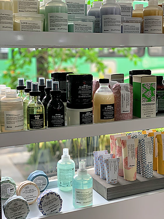 Repisa de productos Davines frente a la ventana, con los árboles de la calle detrás